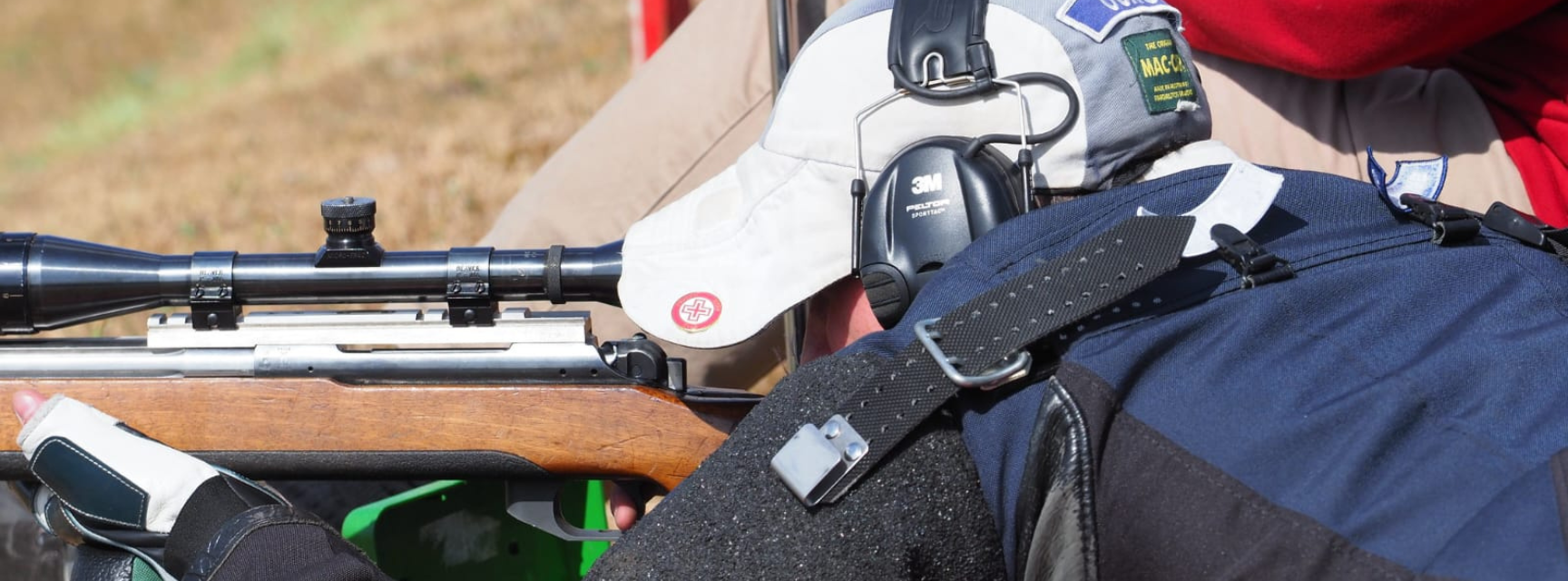 A man shooting a rifle from a prone position on the grass