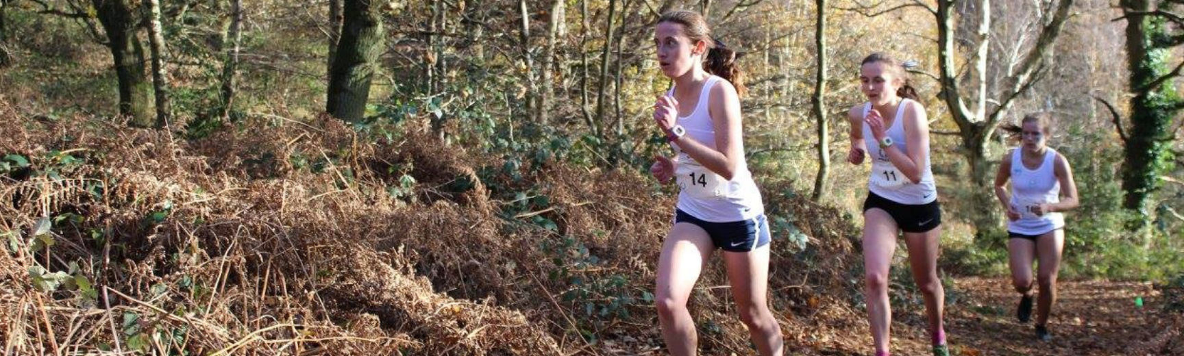 Three women running through a wood during the Oxford vs Cambridge Varsity race