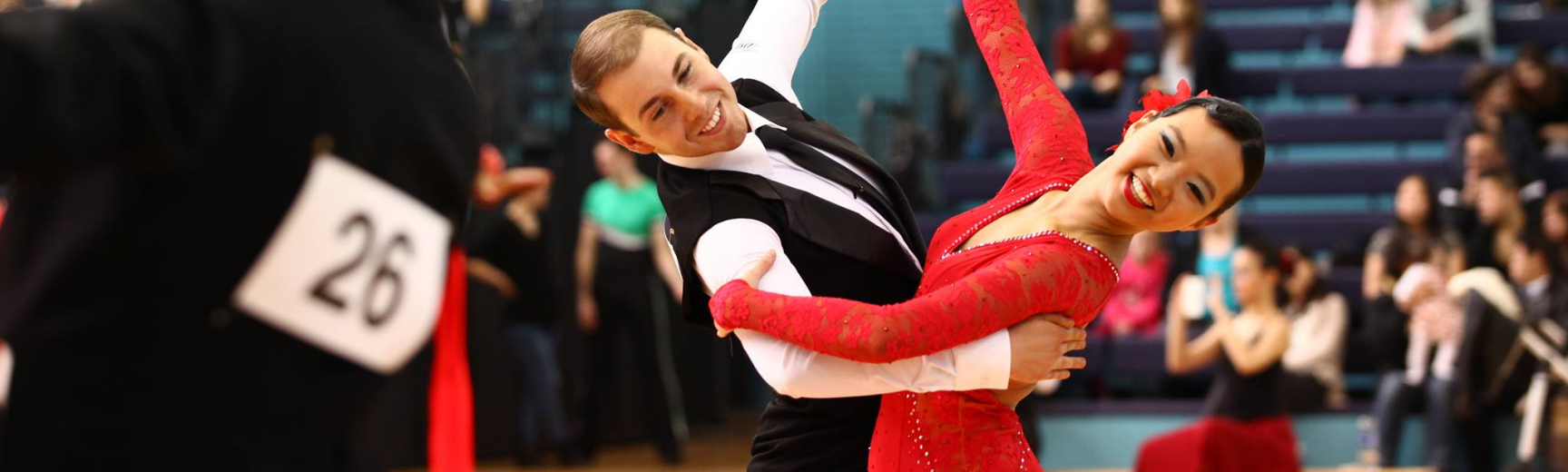 Dancesport banner A man in a tuxedo dancing with a women in a red dress in a dancing competition