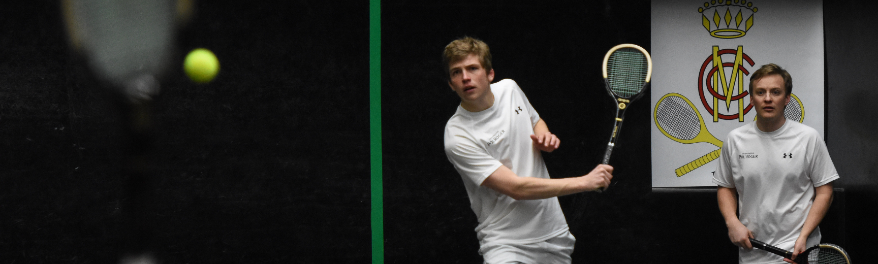 Two men playing real tennis with wooden rackets