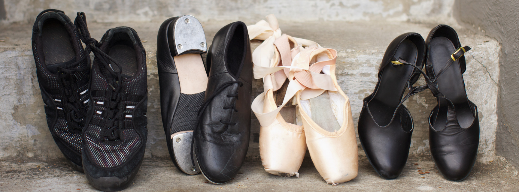 Dancing shoes of all different varieties laid out on a stone step