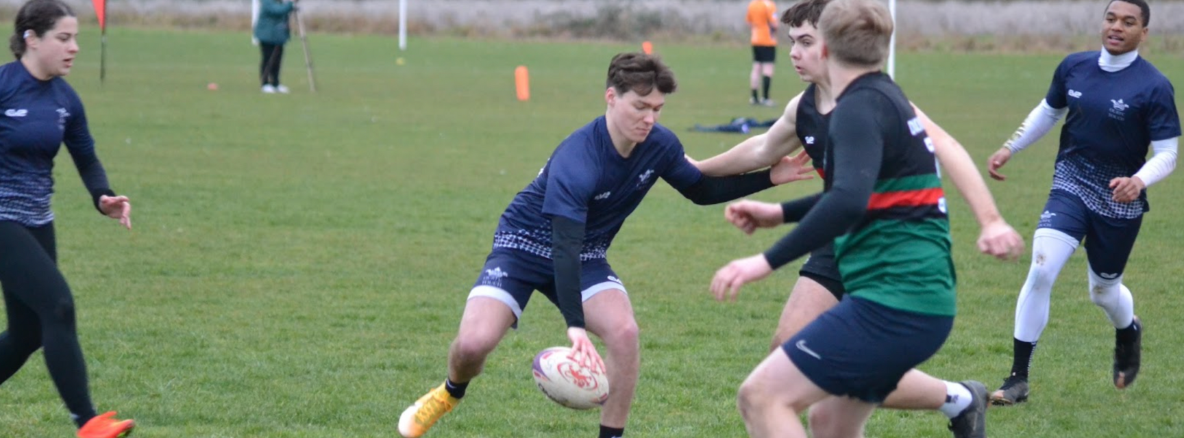 Four Oxford students playing touch rugby again an opposing team on a grass pitch