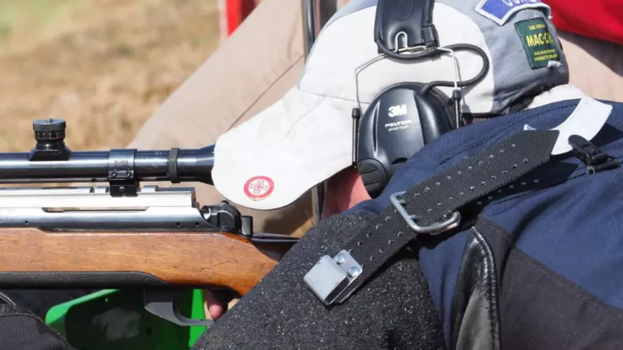A man shooting a rifle from a prone position on the grass