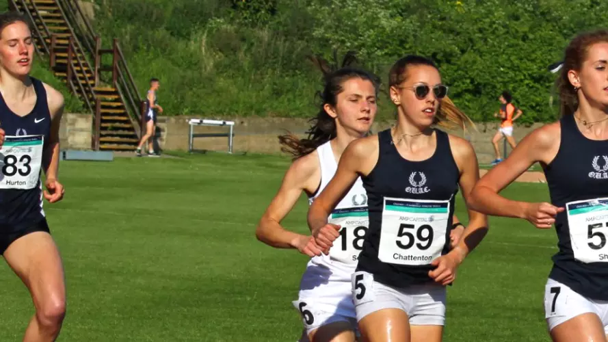 Five women running around the Sir Roger Bannisyer Running track in the Oxford vs Cambridge athletics Varsity match