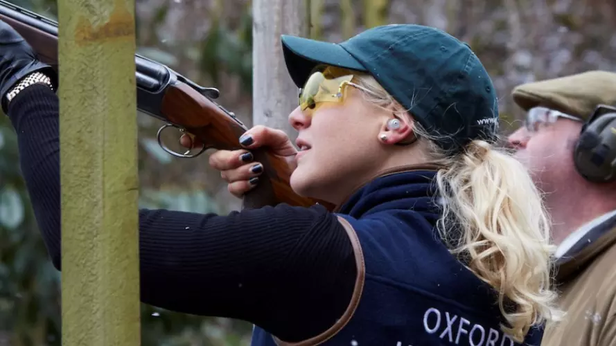 A close up of a woman in Oxford kit shooting a gun