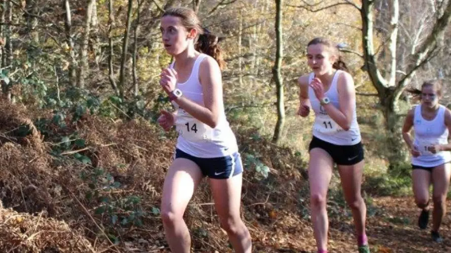 Three women running through a wood during the Oxford vs Cambridge Varsity race