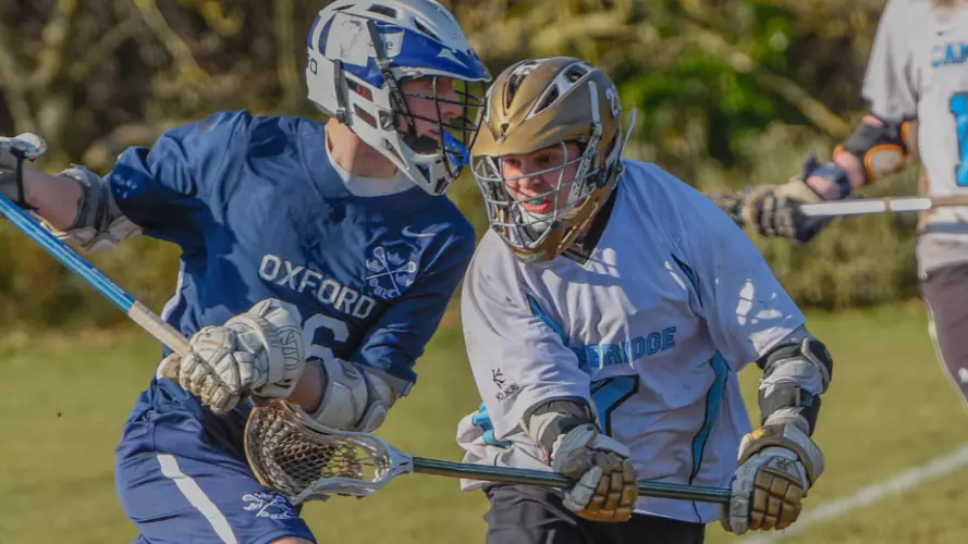 Two men duelling for the ball in the lacrosse Varsity match, with Oxford in possession against Cambridge