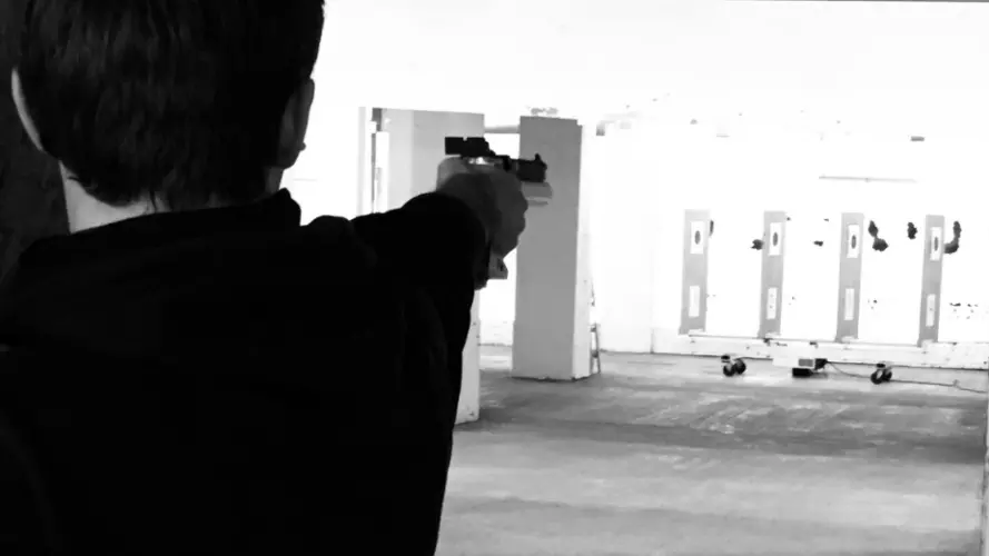A person shooting towards a target with a pistol
