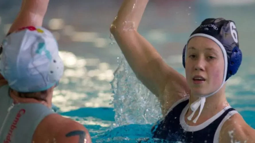 Two women playing water polo in the Oxford vs Cambridge Varsity match