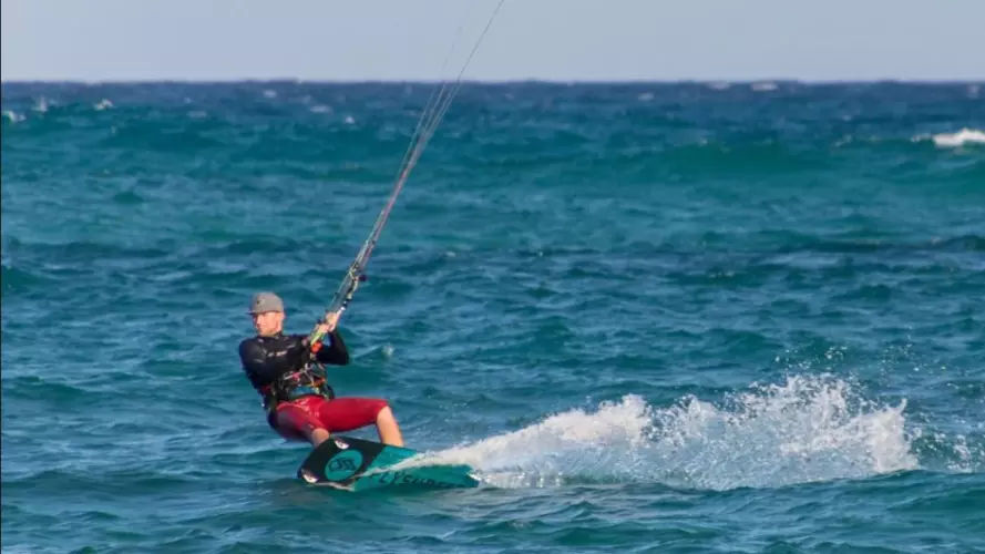 One windsurfer and one kitesurfer enjoying the waves in the sun